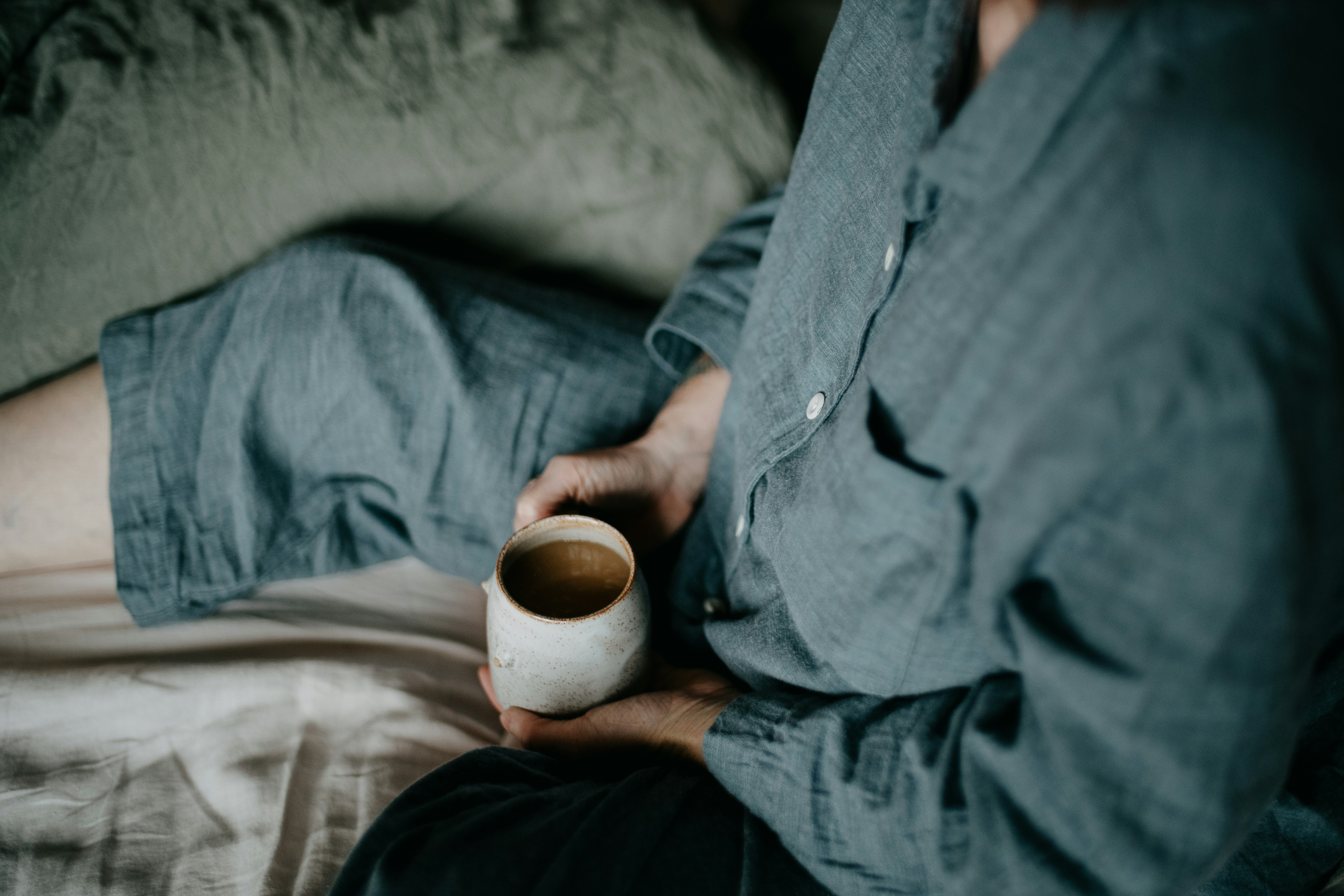 a person sitting on a bed holding a cup