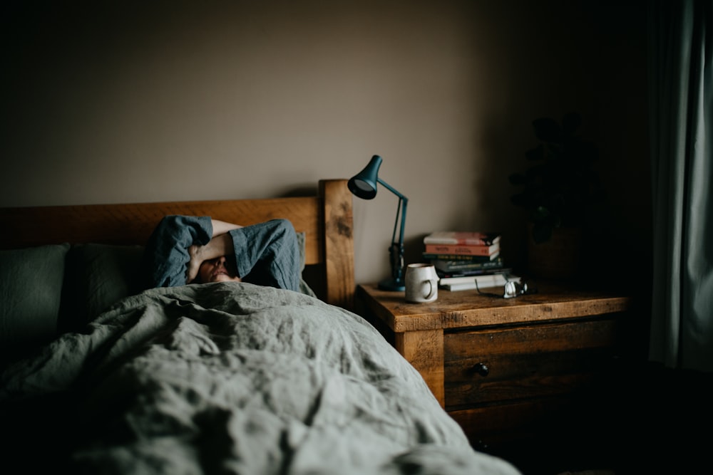 Una persona acostada en la cama debajo de una manta