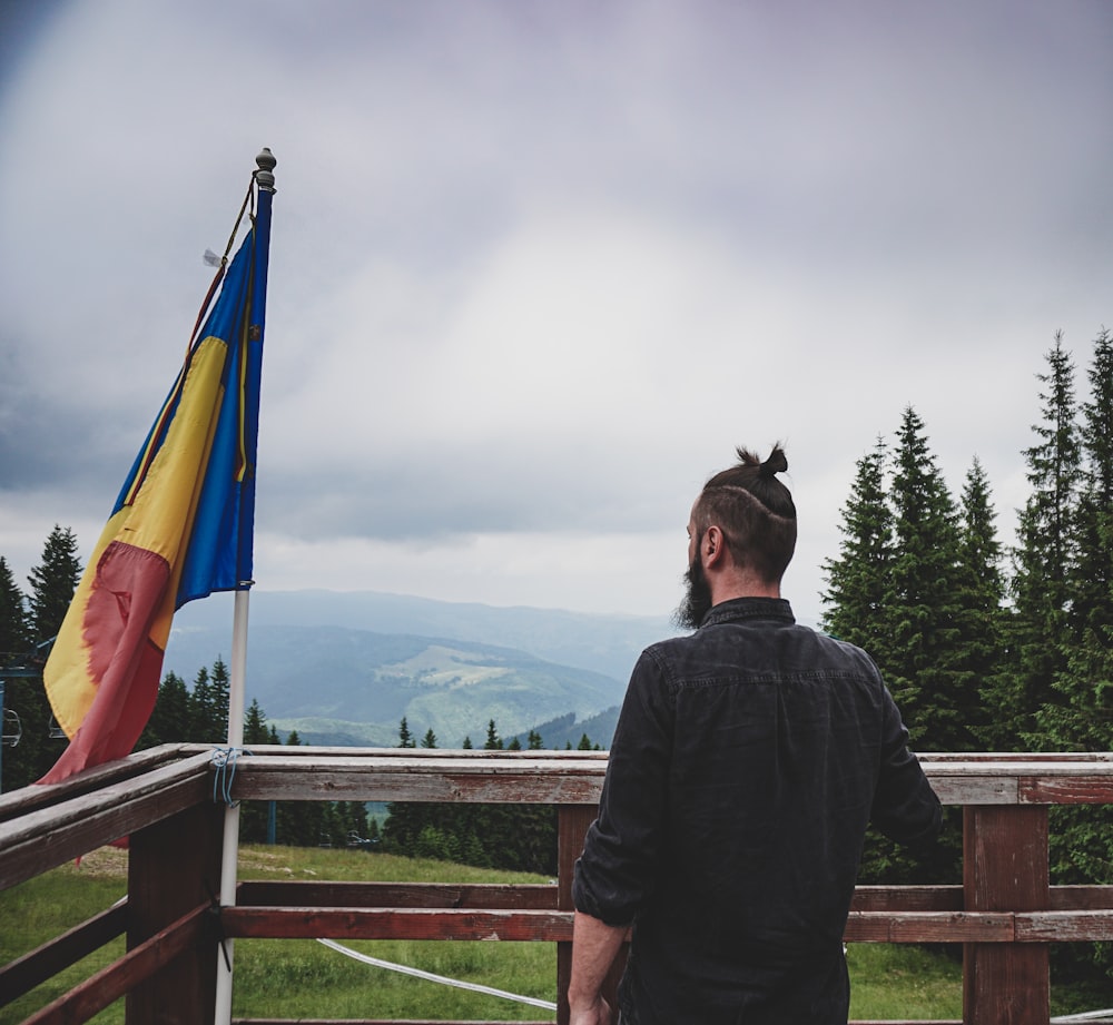 a man standing on top of a wooden deck next to a flag