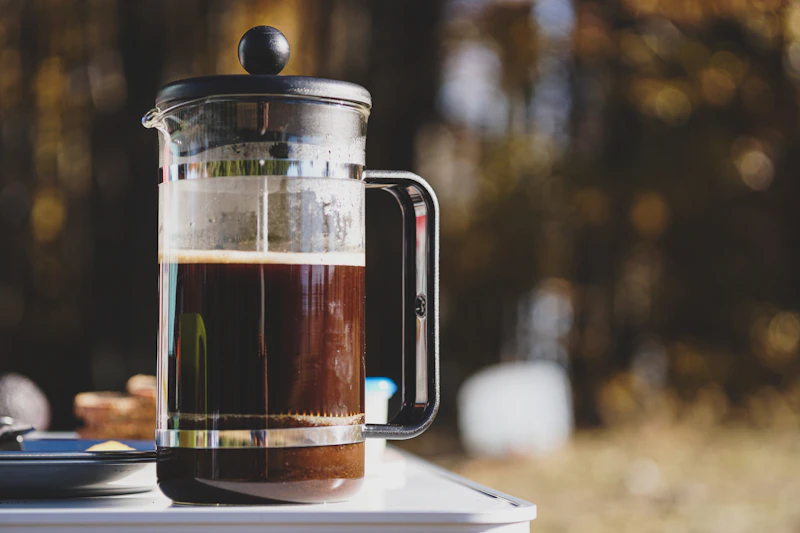 Glass French press filled with dark brewed coffee on a table