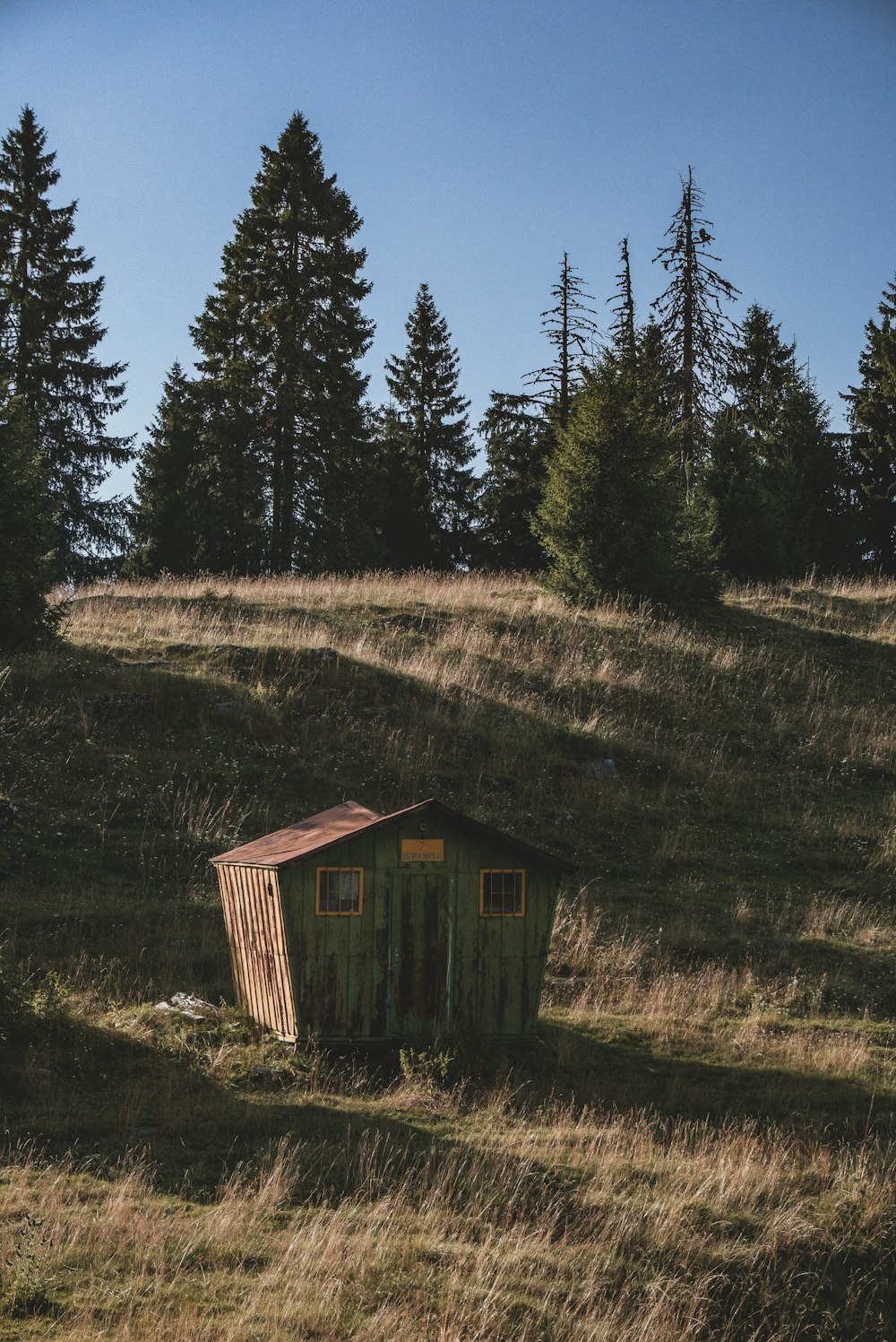 a small outhouse in the middle of a grassy field