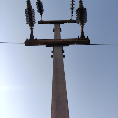 Close-up of a freshly installed high-tension concrete pole standing tall against a clear sky.