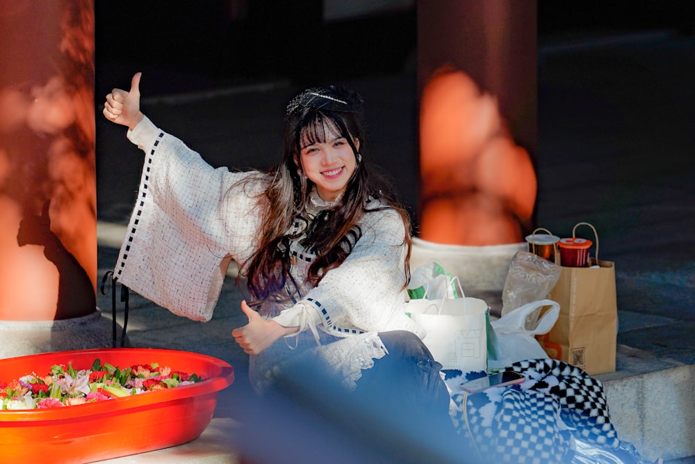 a woman sitting on the ground next to a bowl of food