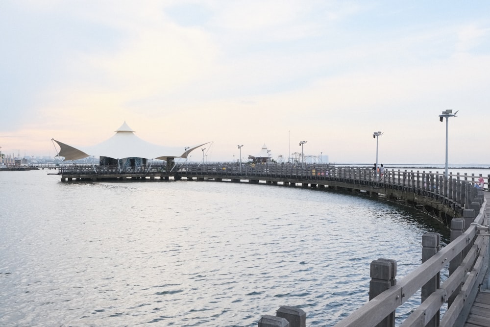 a pier on the water with a large white tent in the background