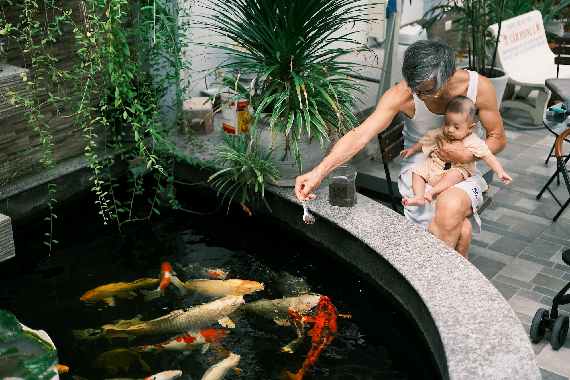 a woman and a child are looking at fish in a pond