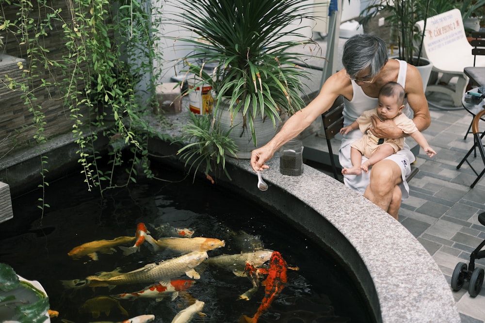 Eine Frau und ein Kind betrachten Fische in einem Teich