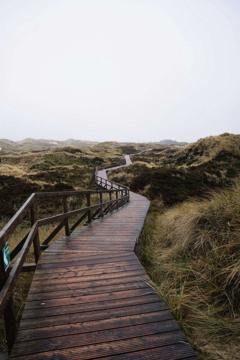 a wooden walkway leading to a grassy hill