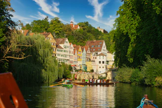 a row boat on a river with a row of houses in the background