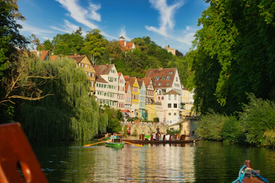 a row boat on a river with a row of houses in the background