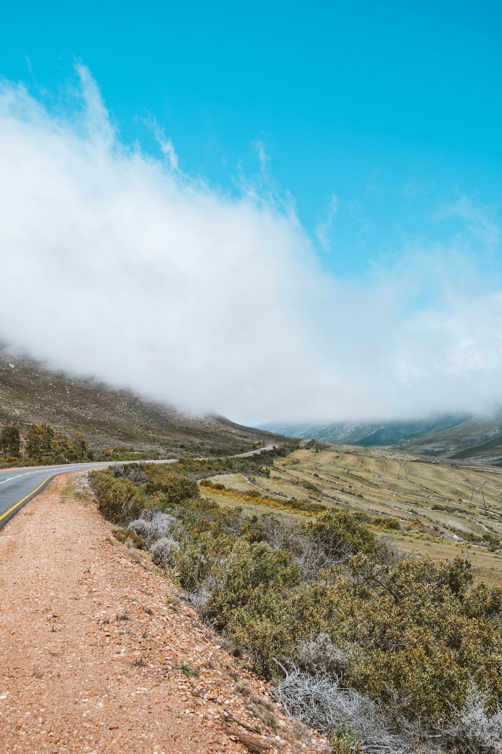 a dirt road on a hill side with a blue sky in the background