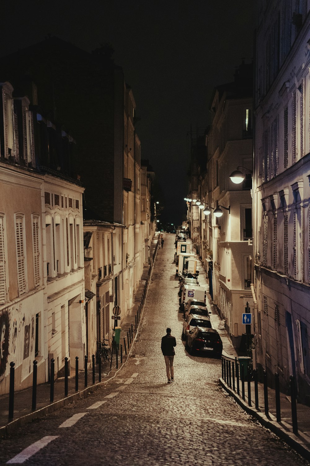 a person walking down a cobblestone street at night