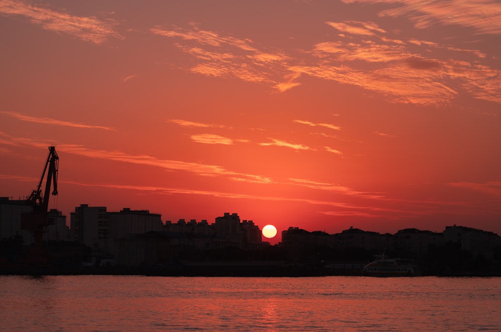 the sun is setting over a city on the water