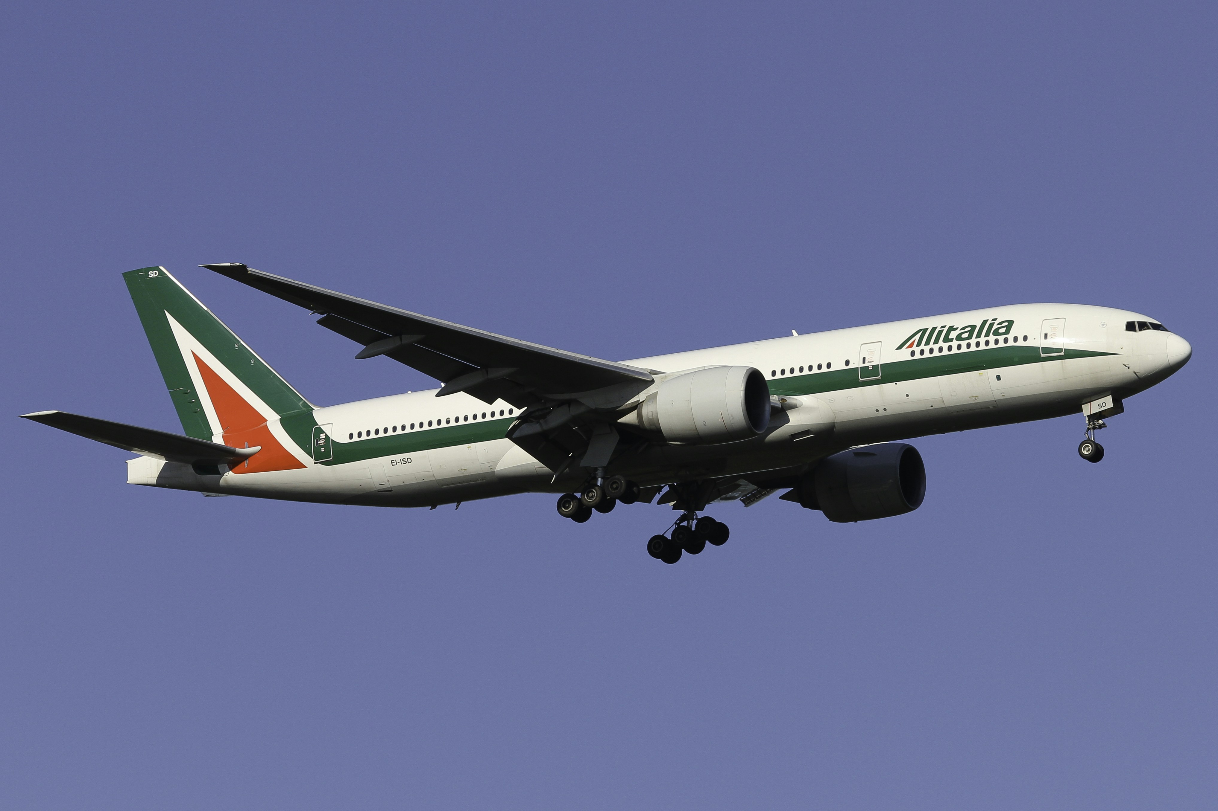a large jetliner flying through a blue sky, Alitalia Boeing 777-200ER landing on runway 35L at Milan Malpensa Airport
