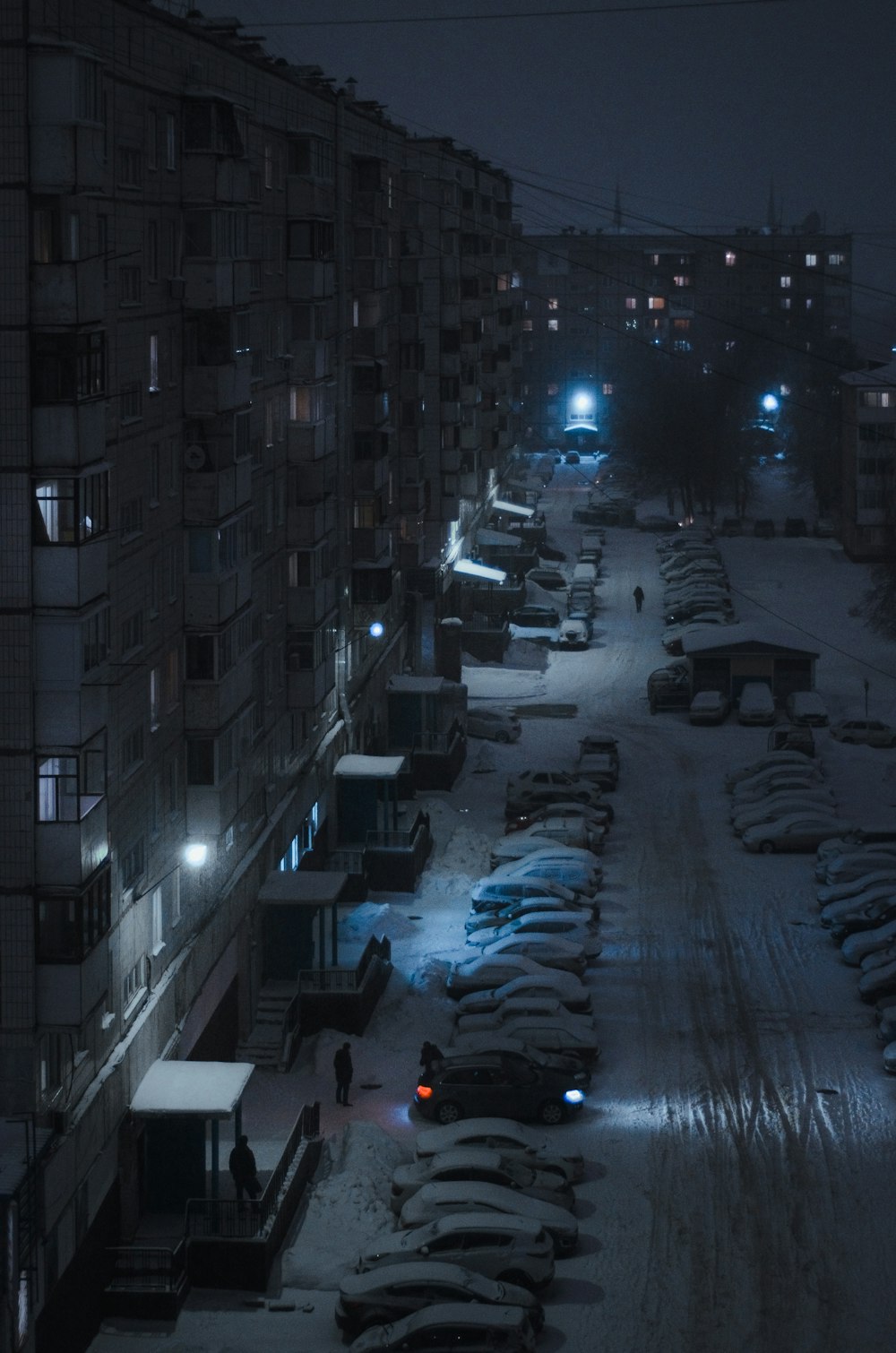 a snow covered parking lot next to a building at night