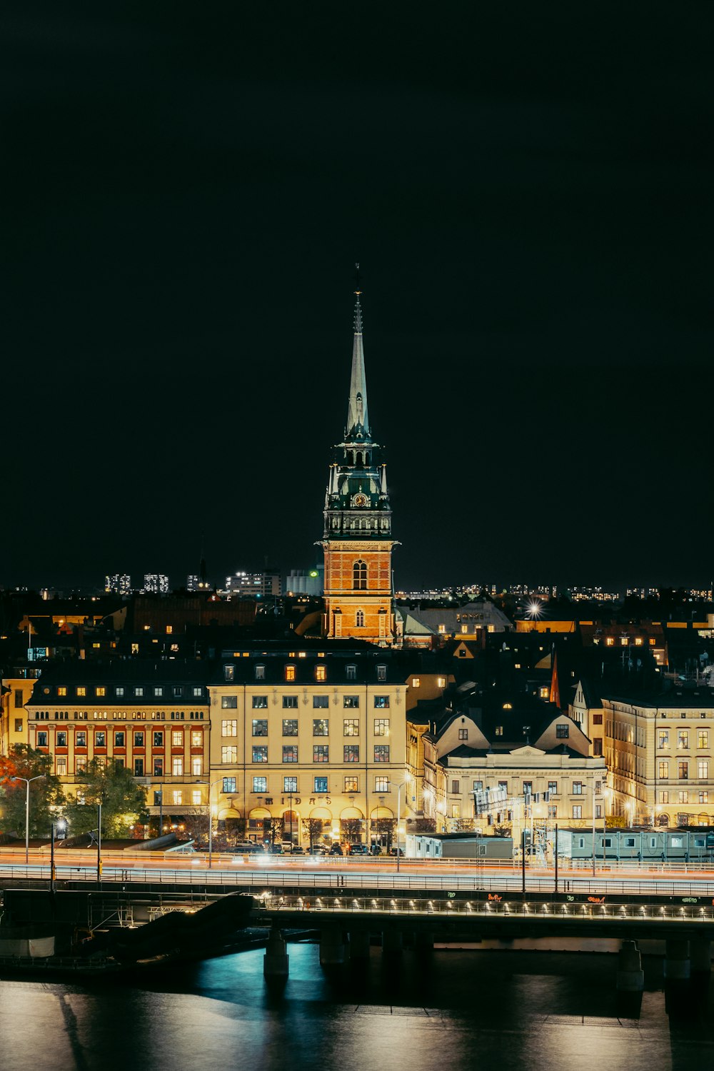 a night view of a city with a bridge and a clock tower