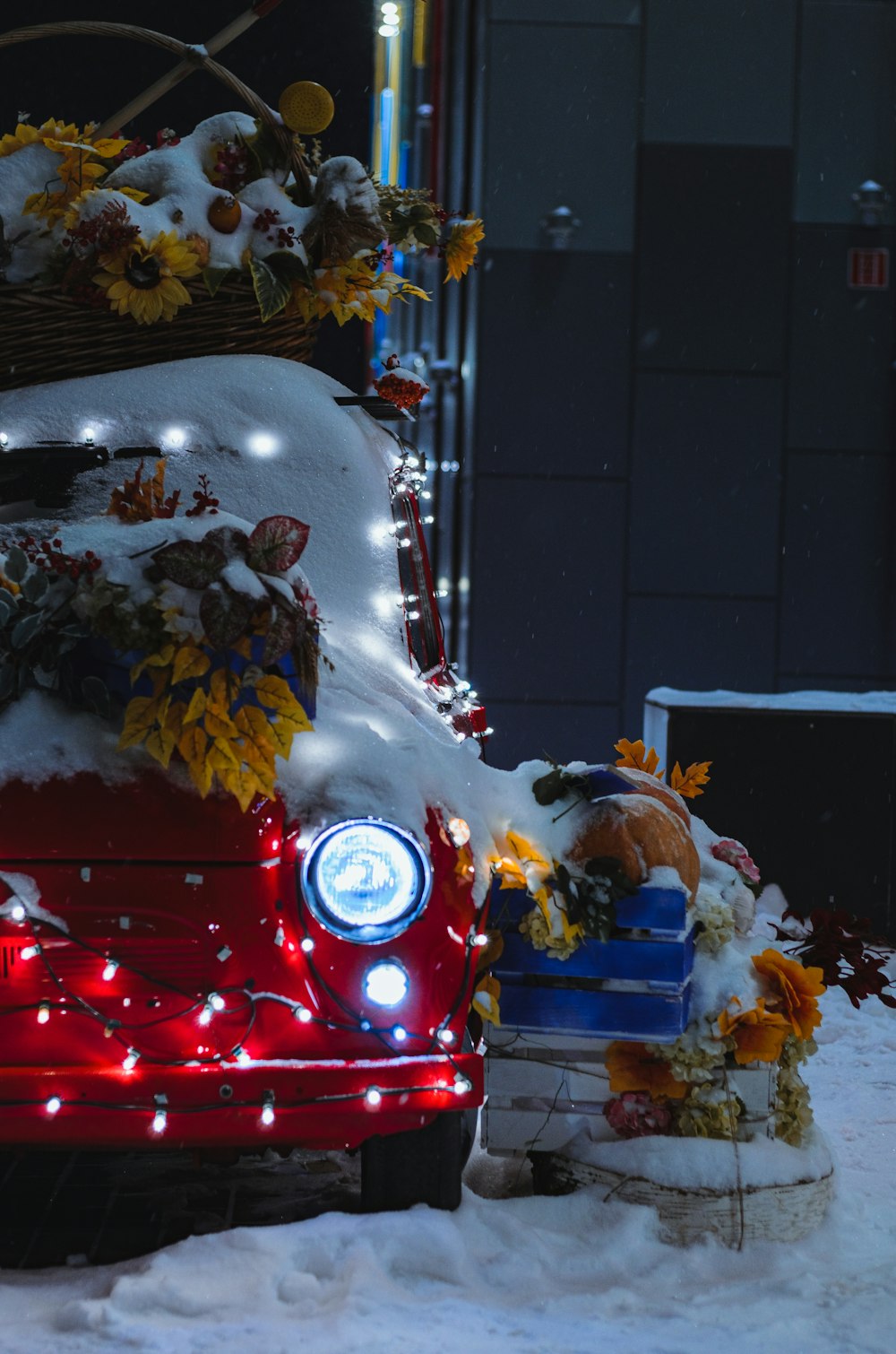 a red car covered in snow with christmas lights