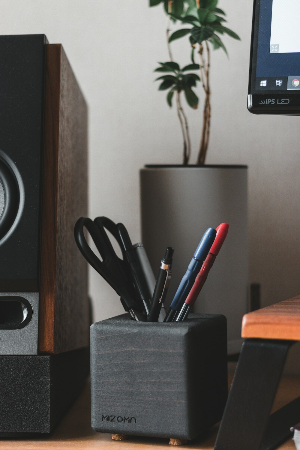 a desk with a speaker and pens and pencils