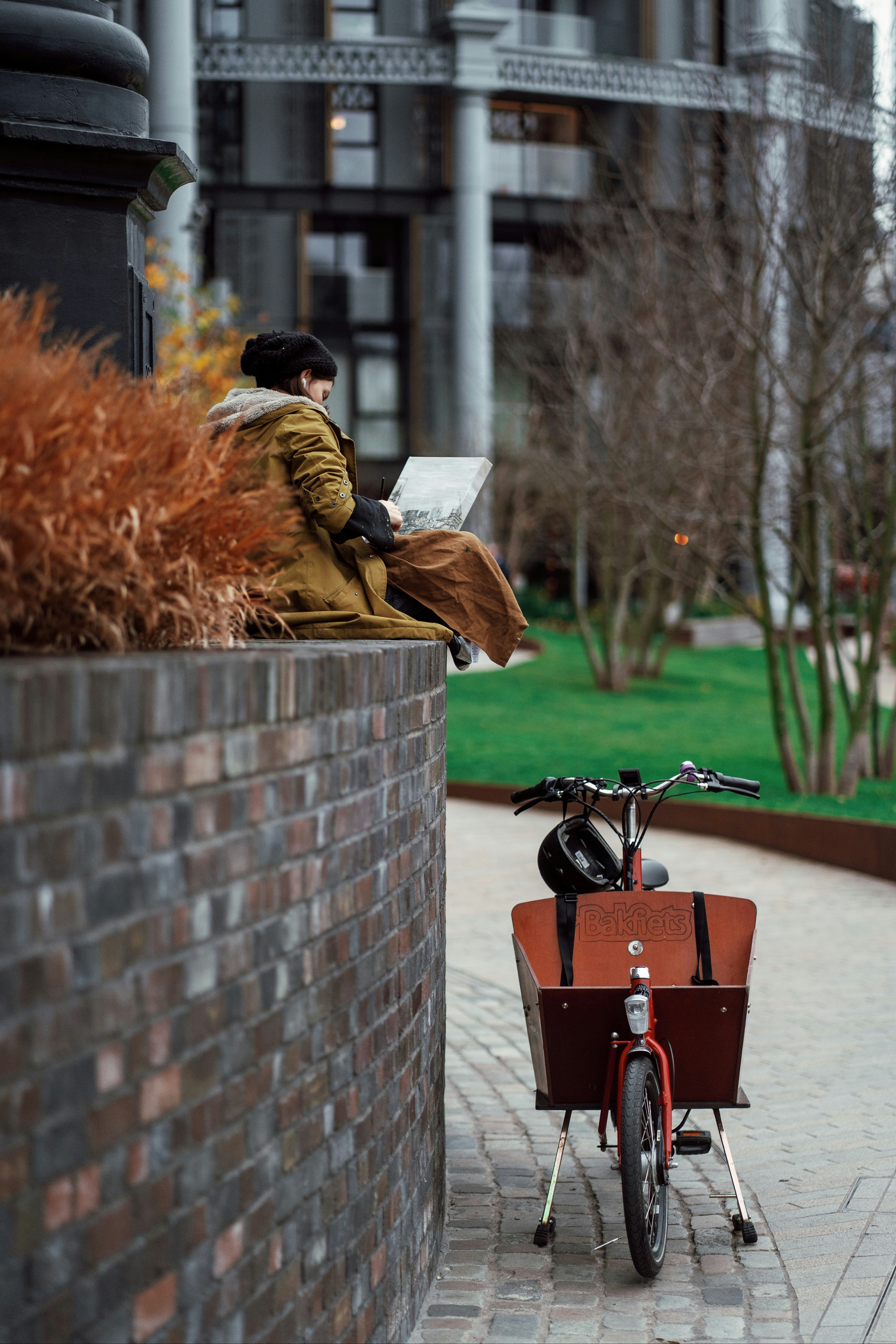 a man sitting on a brick wall next to a bike
