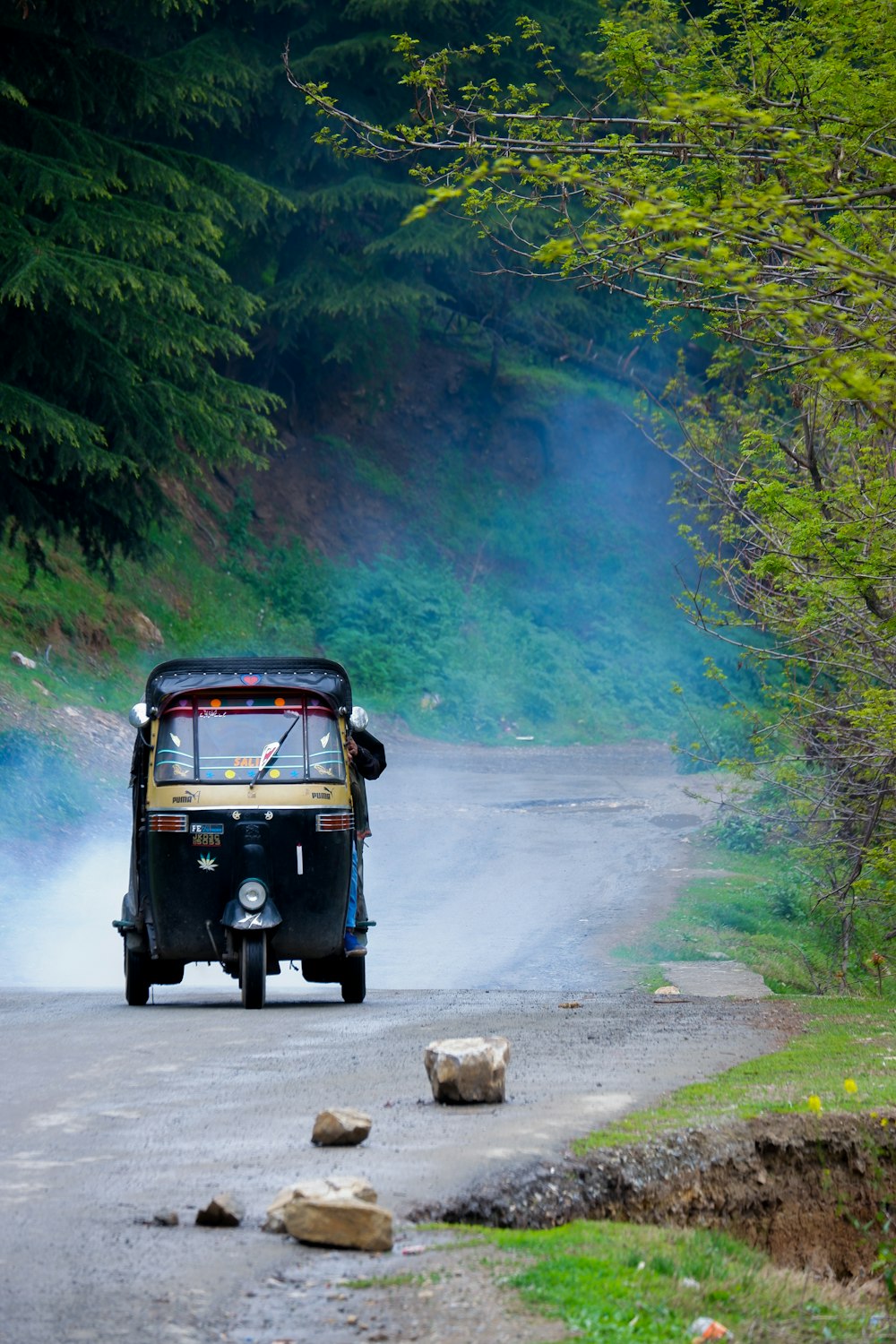 a tuk - tuk driving down a road with smoke coming out of the