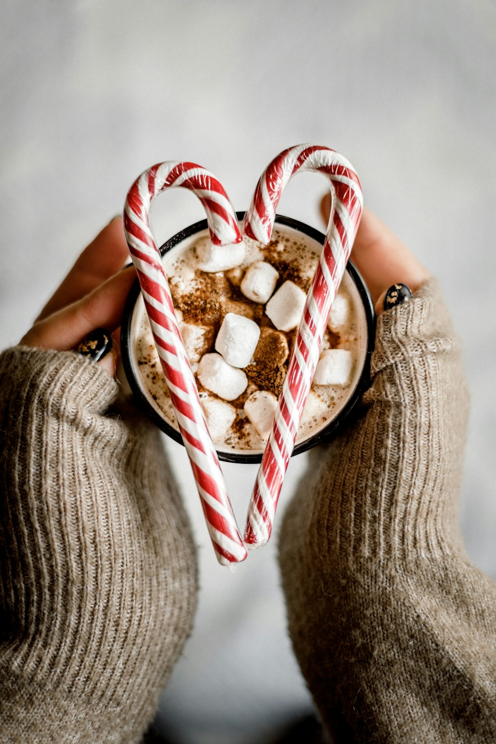 a person holding a cup of hot chocolate with marshmallows in it