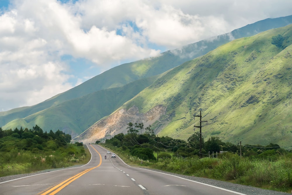 a car driving down a road with a mountain in the background