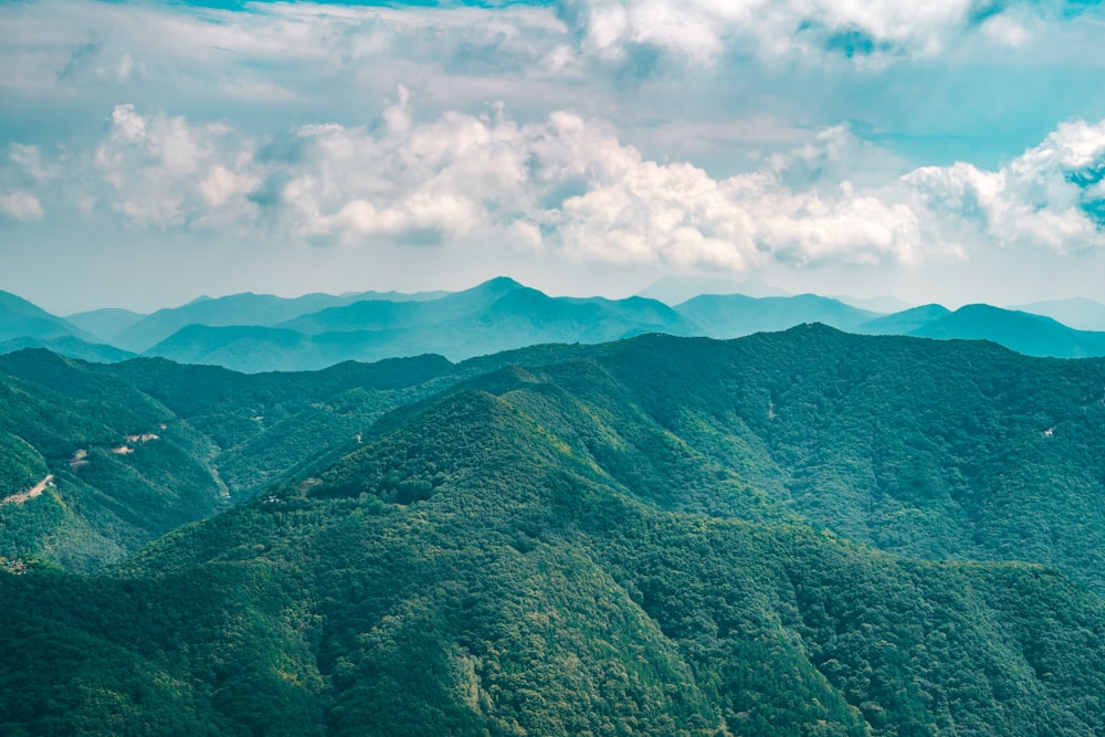 a scenic view of a mountain range with a winding road in the foreground