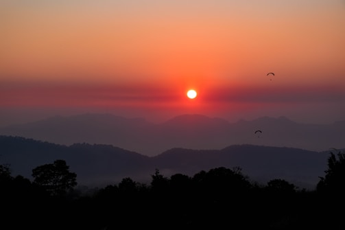 A vibrant sunset view over Mandar Parvat with pilgrims ascending the spiritual hill.