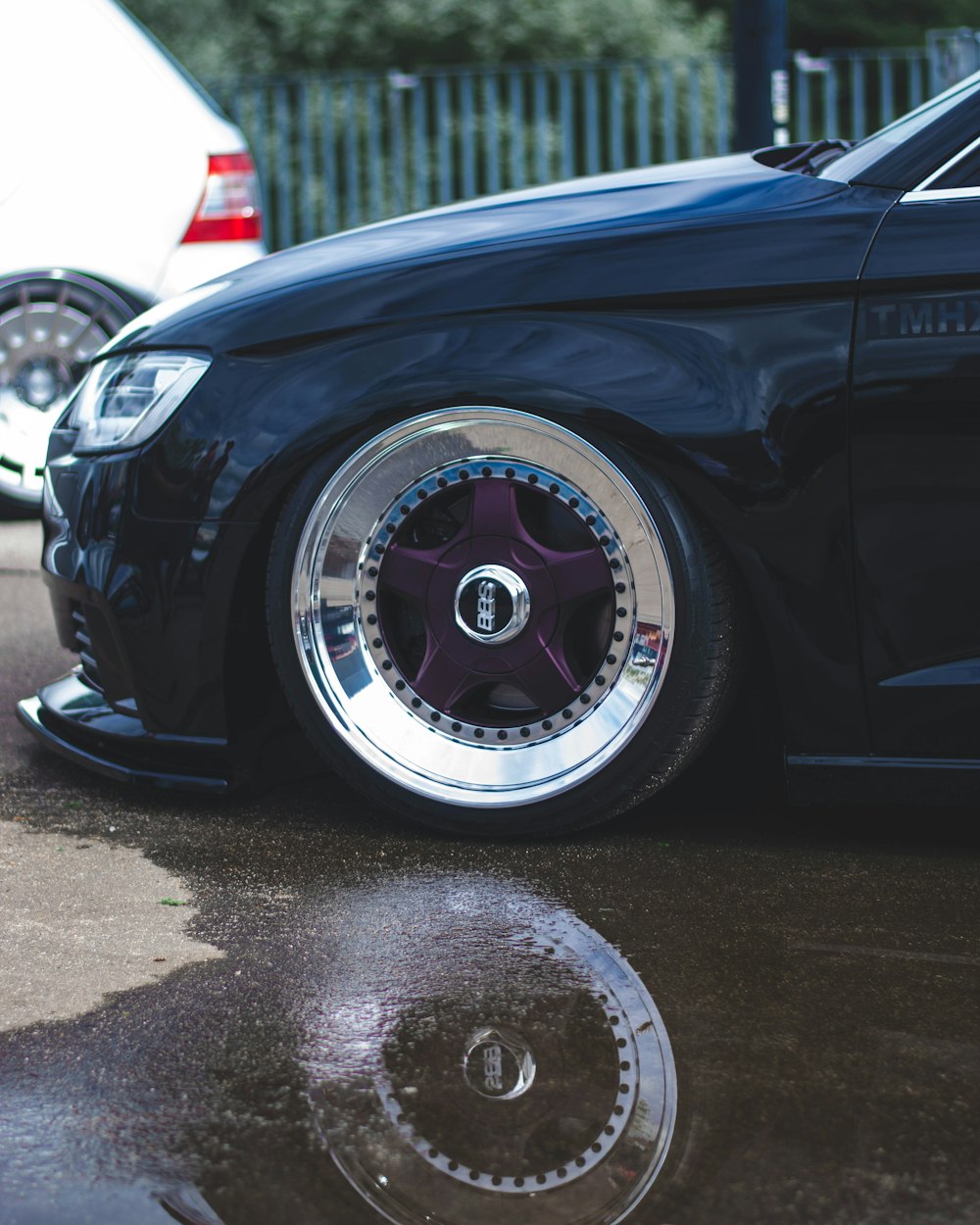 a black car with chrome rims parked in a parking lot