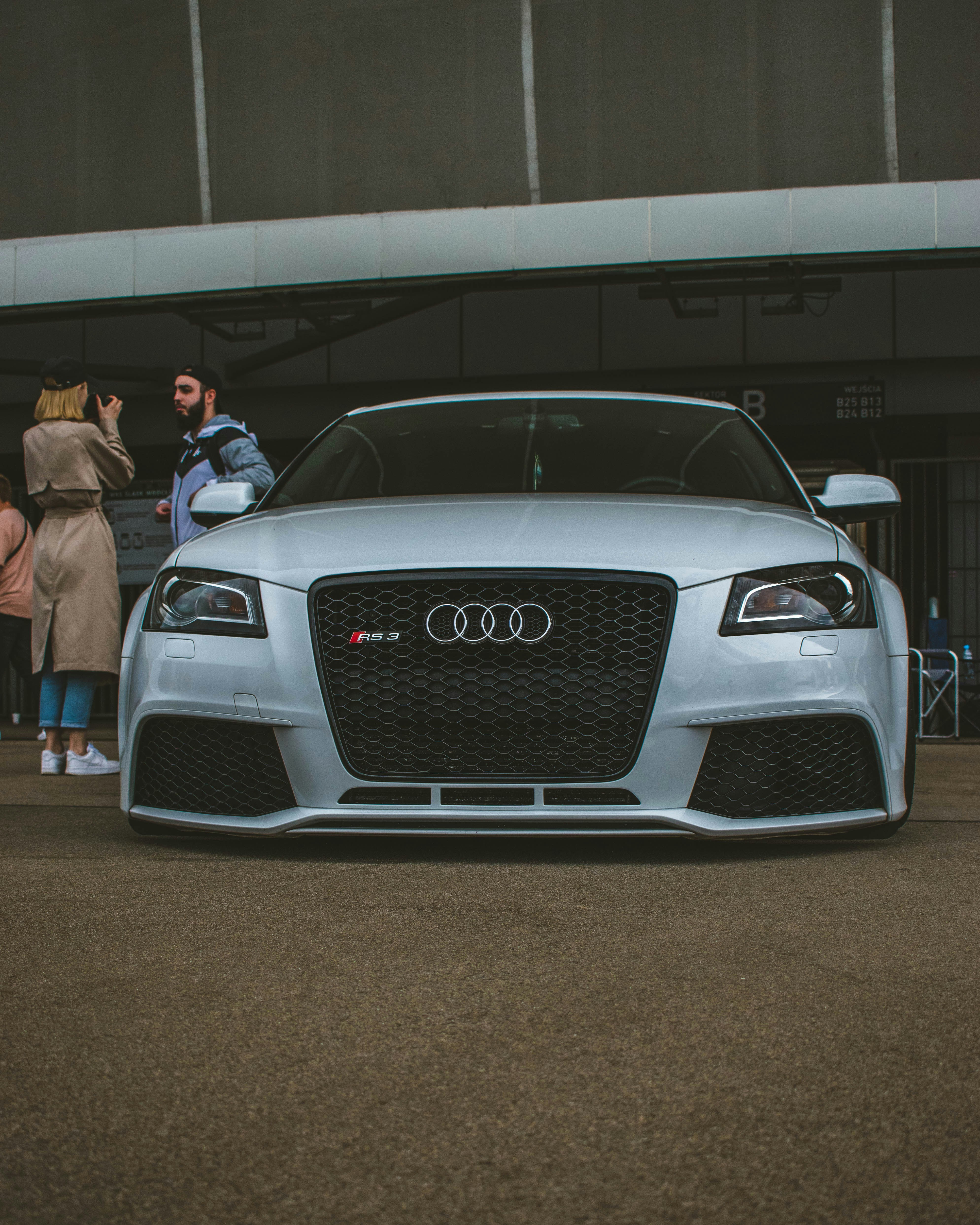 a silver car parked in front of a group of people
