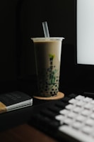 a cup of coffee sitting next to a computer keyboard