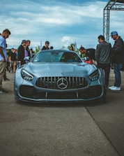 a group of people standing around a blue sports car