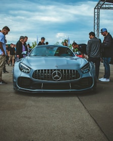 a group of people standing around a blue sports car