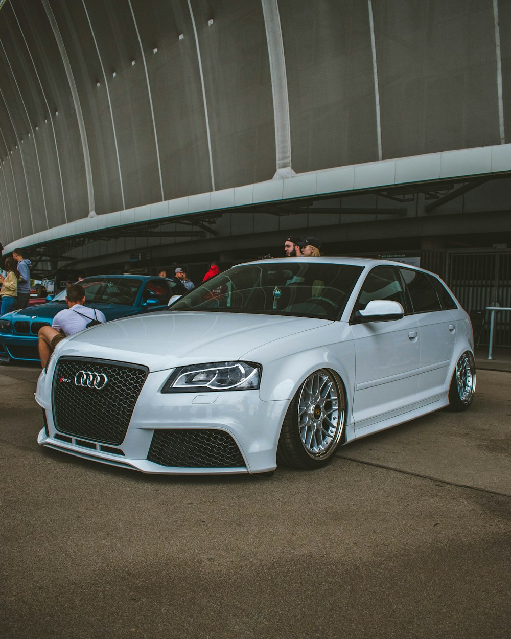 a white car parked in front of a crowd of people