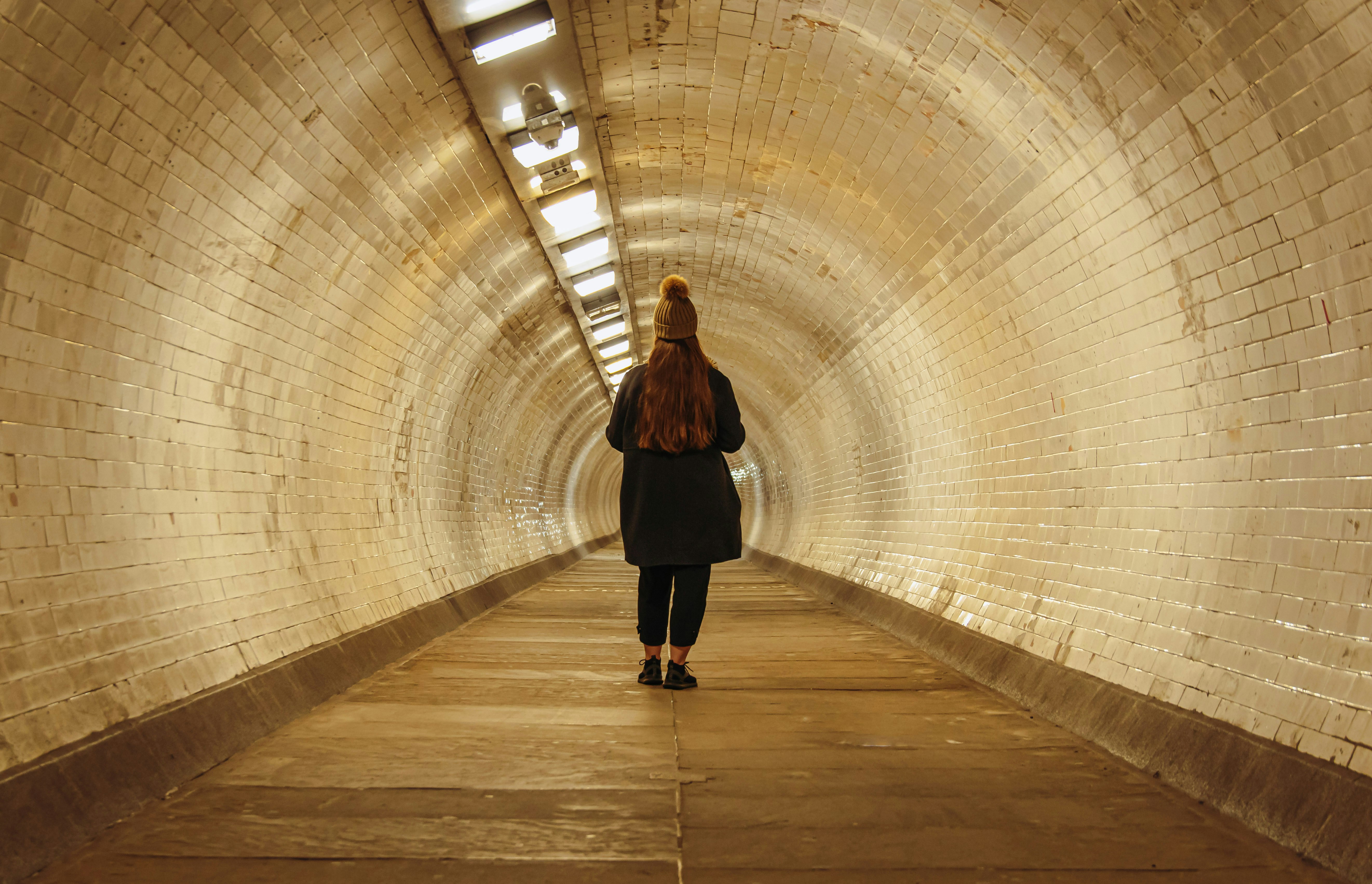 a woman walking through a tunnel with a backpack, 