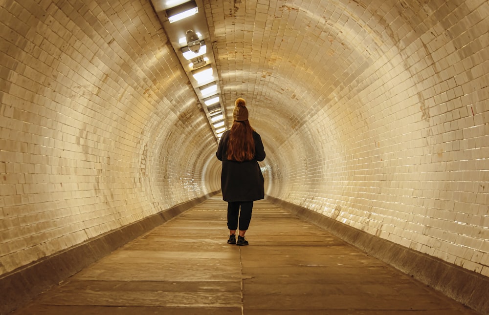 a woman walking through a tunnel with a backpack