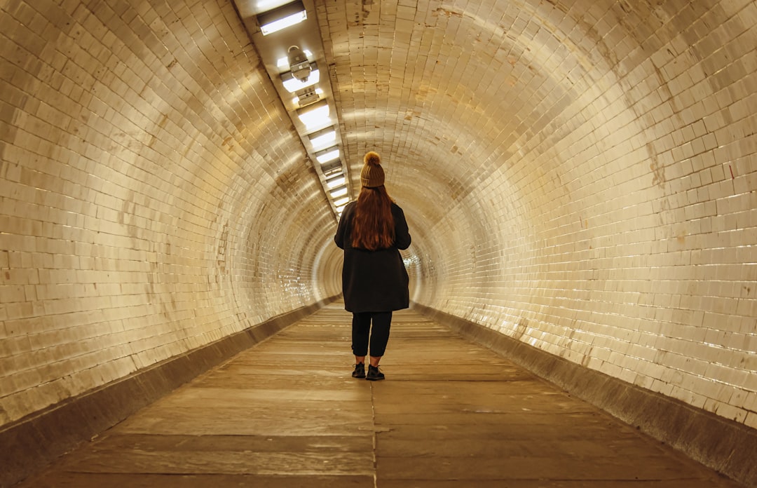 a woman walking through a tunnel with a backpack,