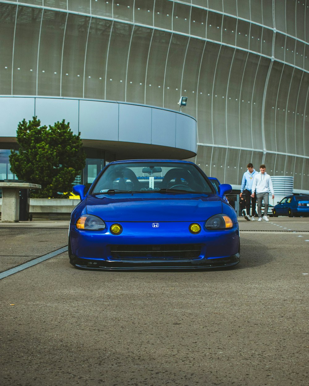 a blue sports car parked in front of a building