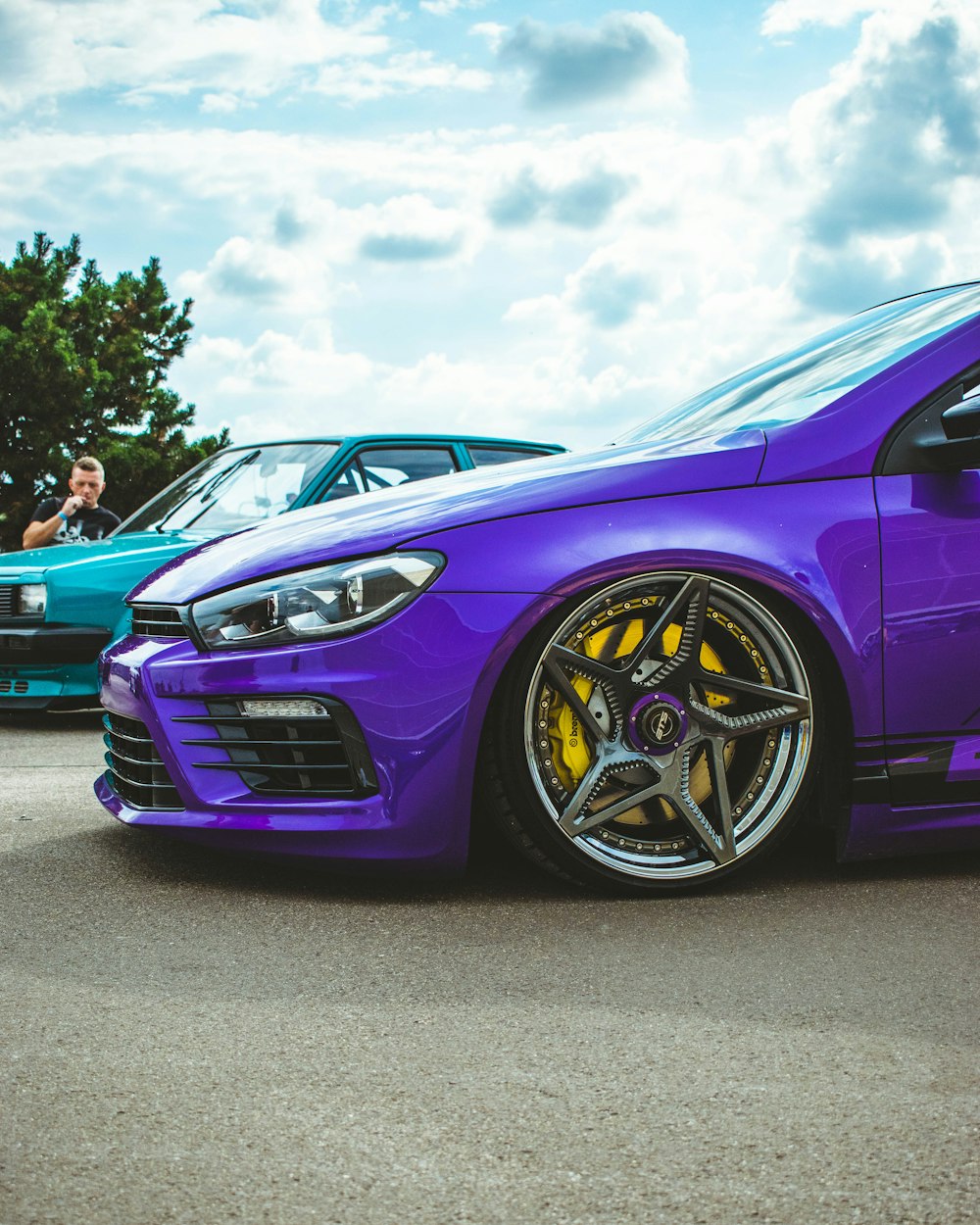 a purple car parked in a parking lot next to other cars