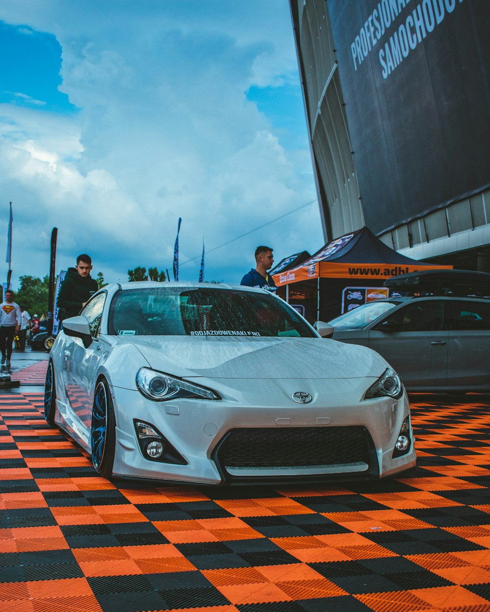 a white sports car parked on a checkered floor