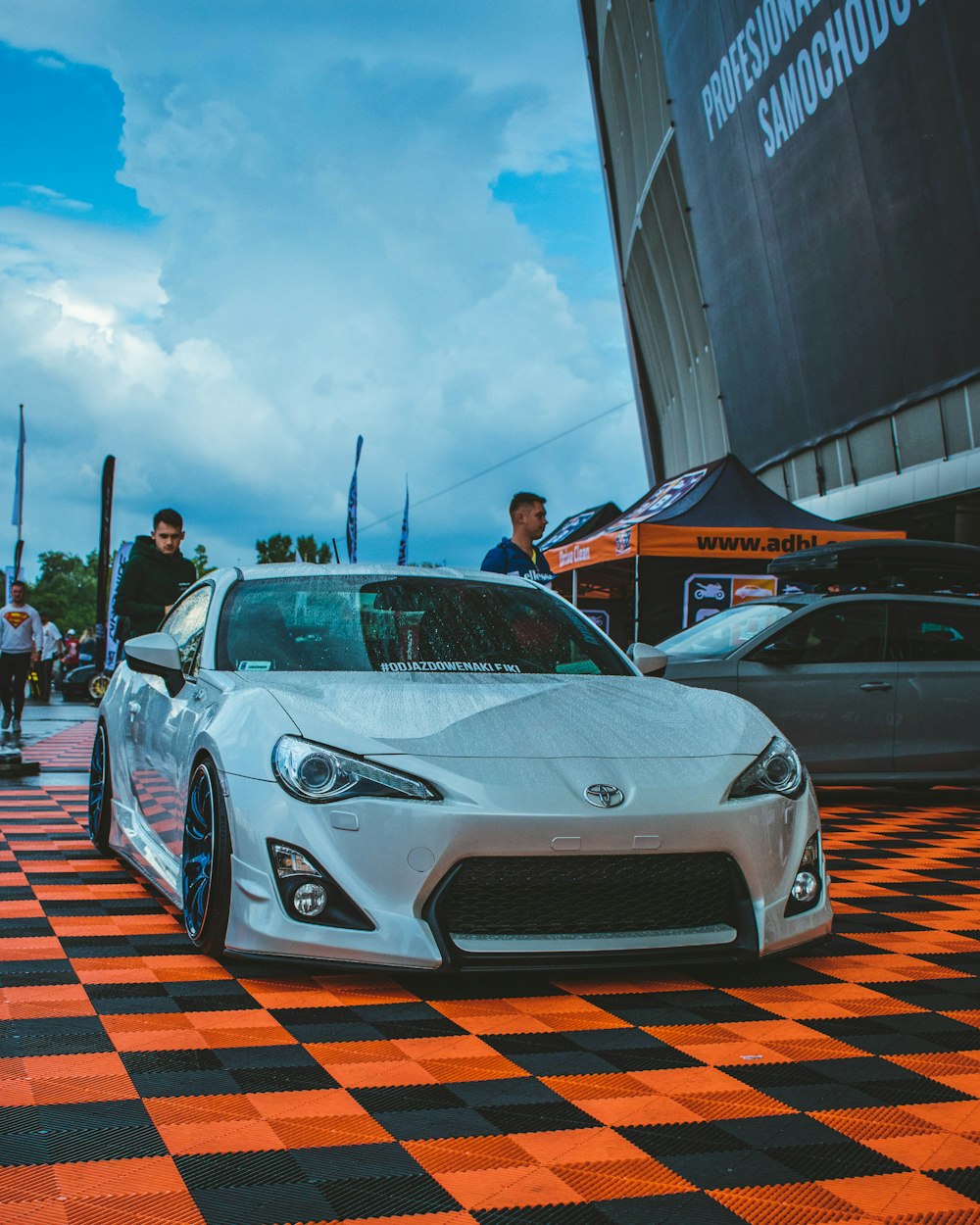 Un auto deportivo blanco estacionado en un piso a cuadros