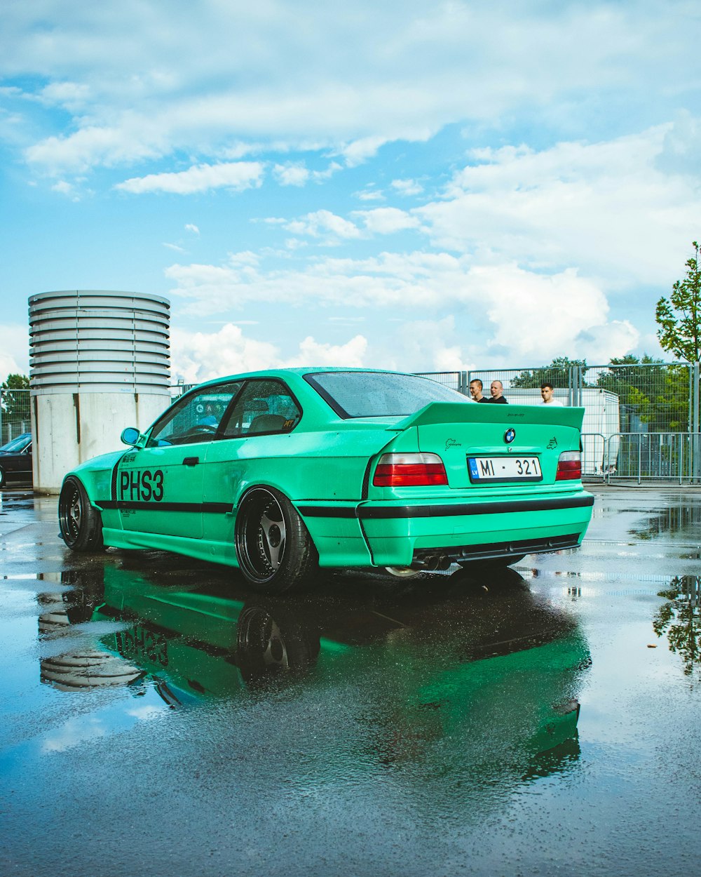 a green car parked on a wet parking lot