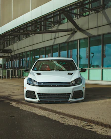 A sparkling white car parked outside a modern office building after a mobile detail.