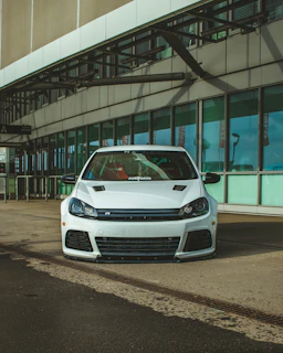 A sparkling white car parked outside a modern office building after a mobile detail.