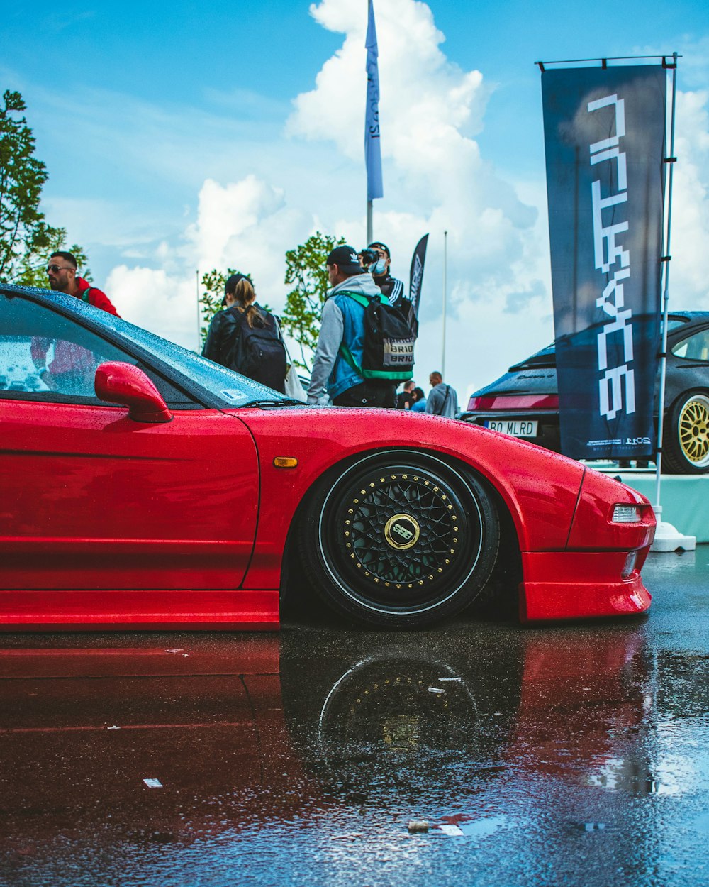 a red sports car parked on a wet parking lot