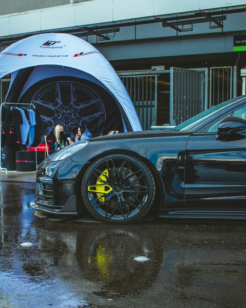 Un'auto sportiva blu parcheggiata davanti a una tenda