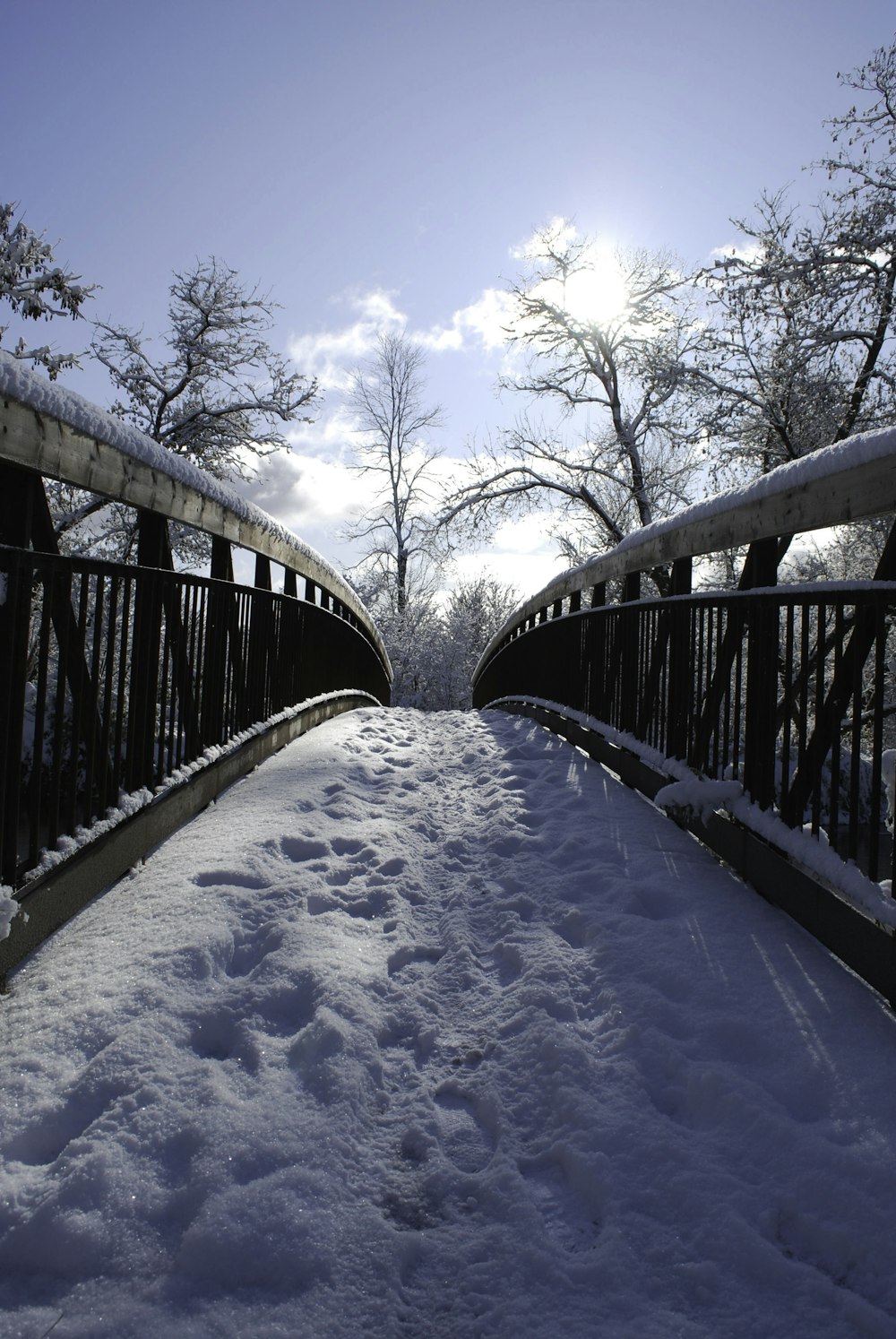 Un puente cubierto de nieve con árboles al fondo