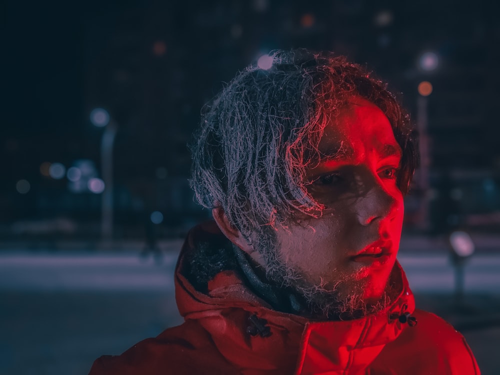 a man in a red jacket standing in the dark