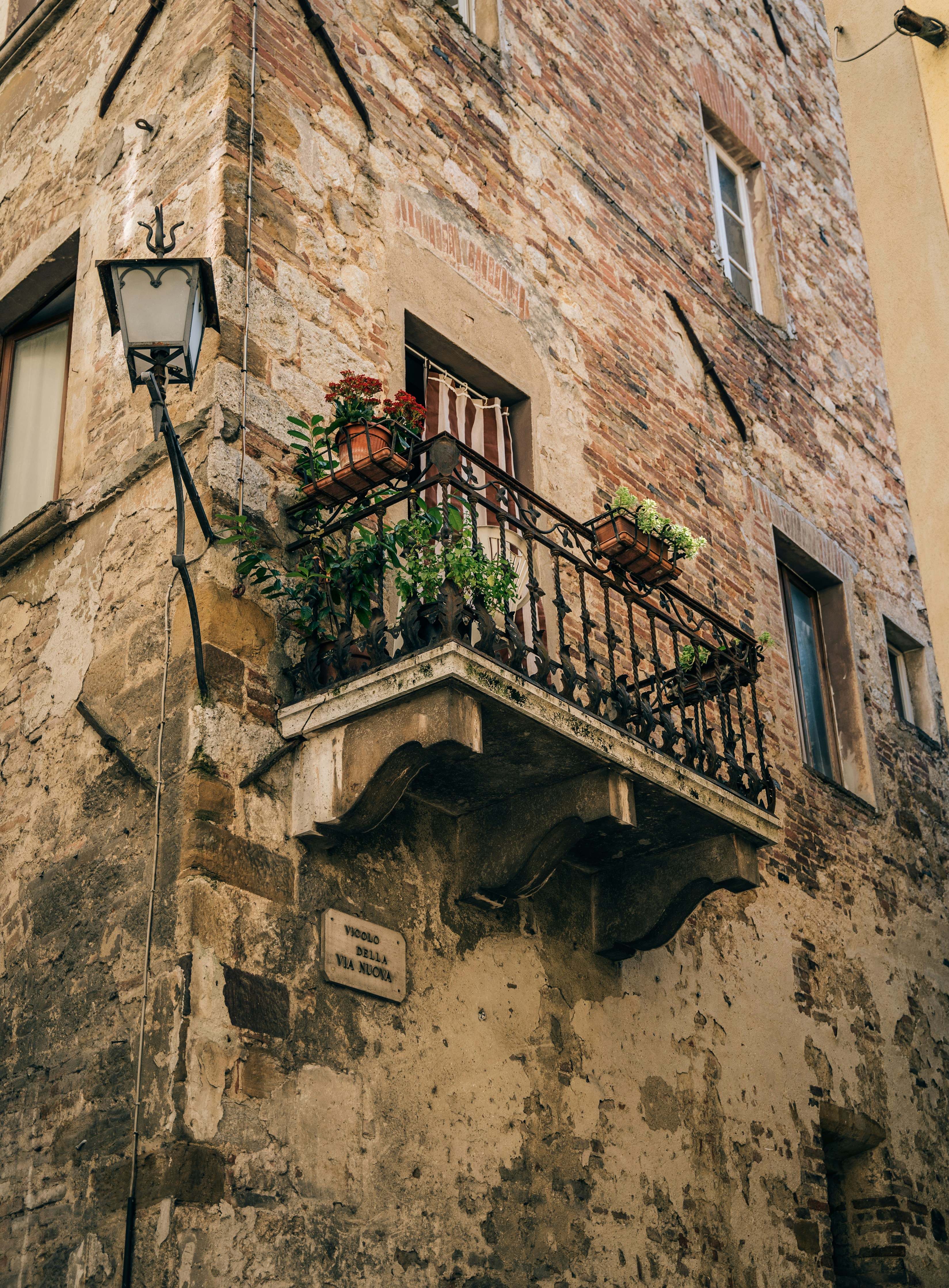 a tall brick building with a balcony with plants on it