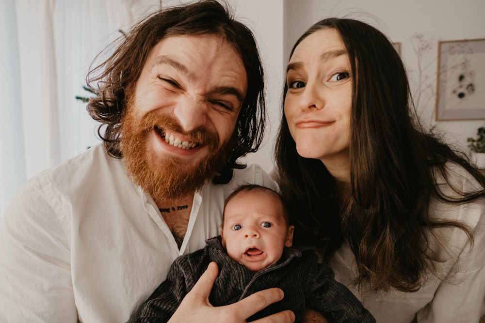 a man and woman holding a baby in their arms