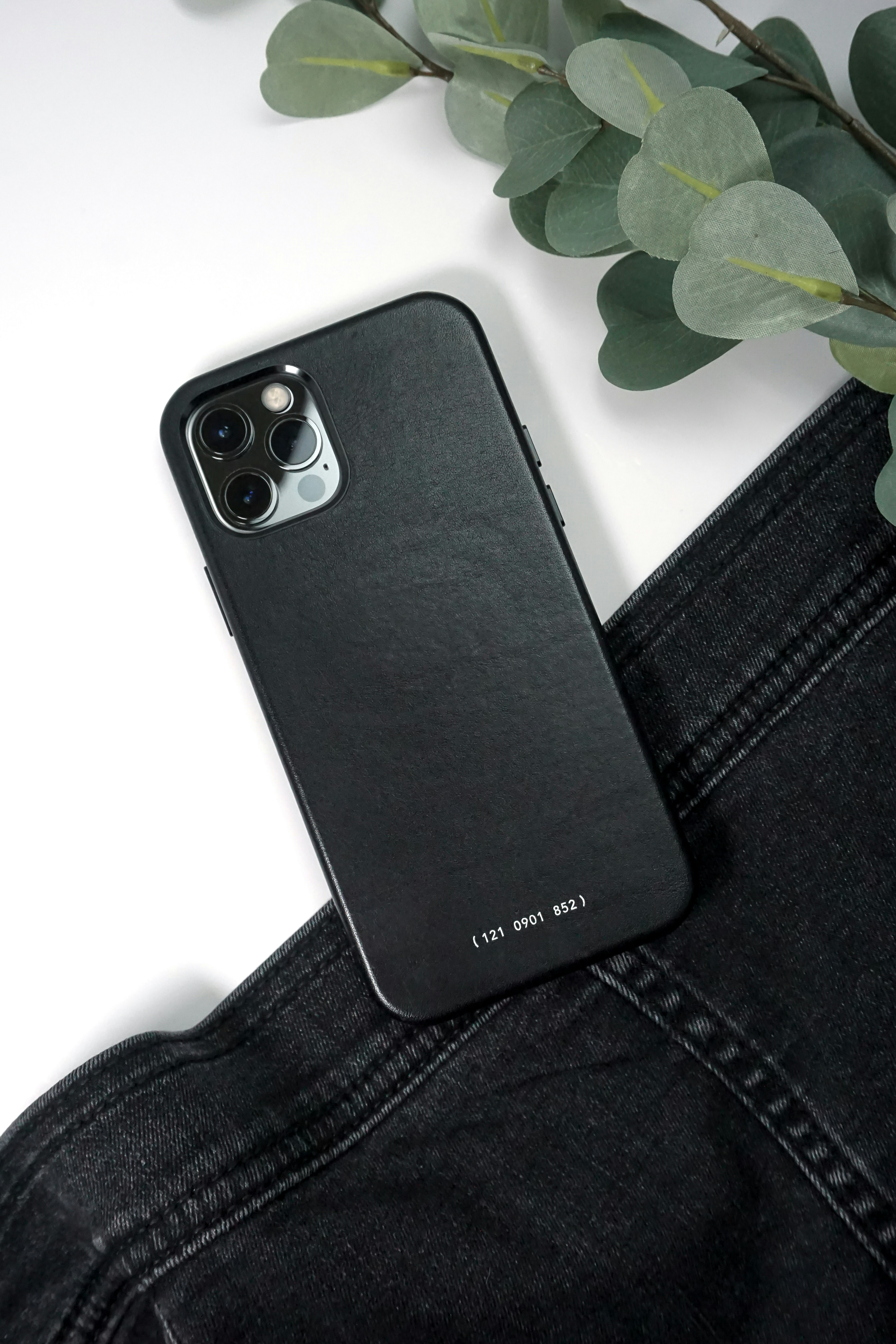 um estojo preto para iphone sentado em cima de um par de jeans